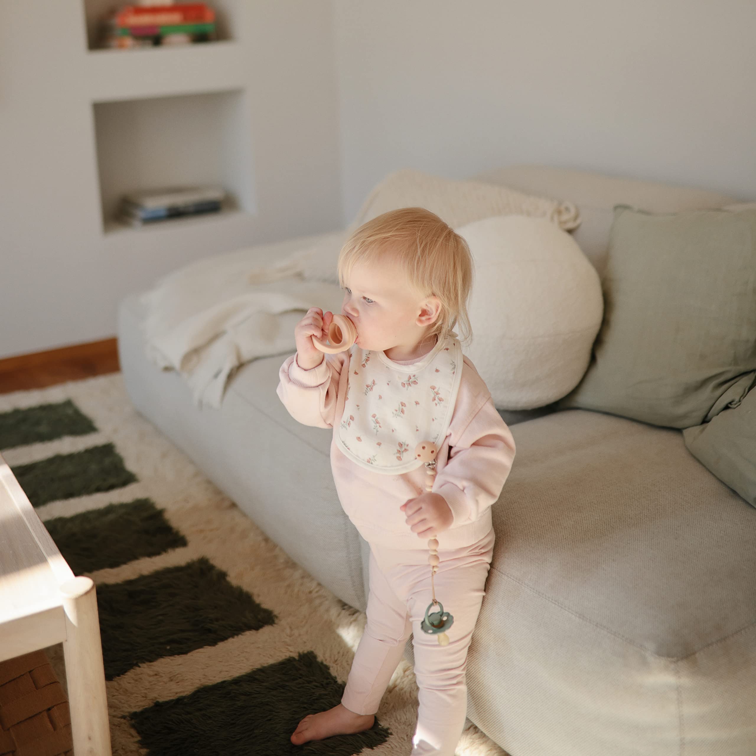 Mushie Luna pacifier clip attached to fabric demonstrating secure everyday use.