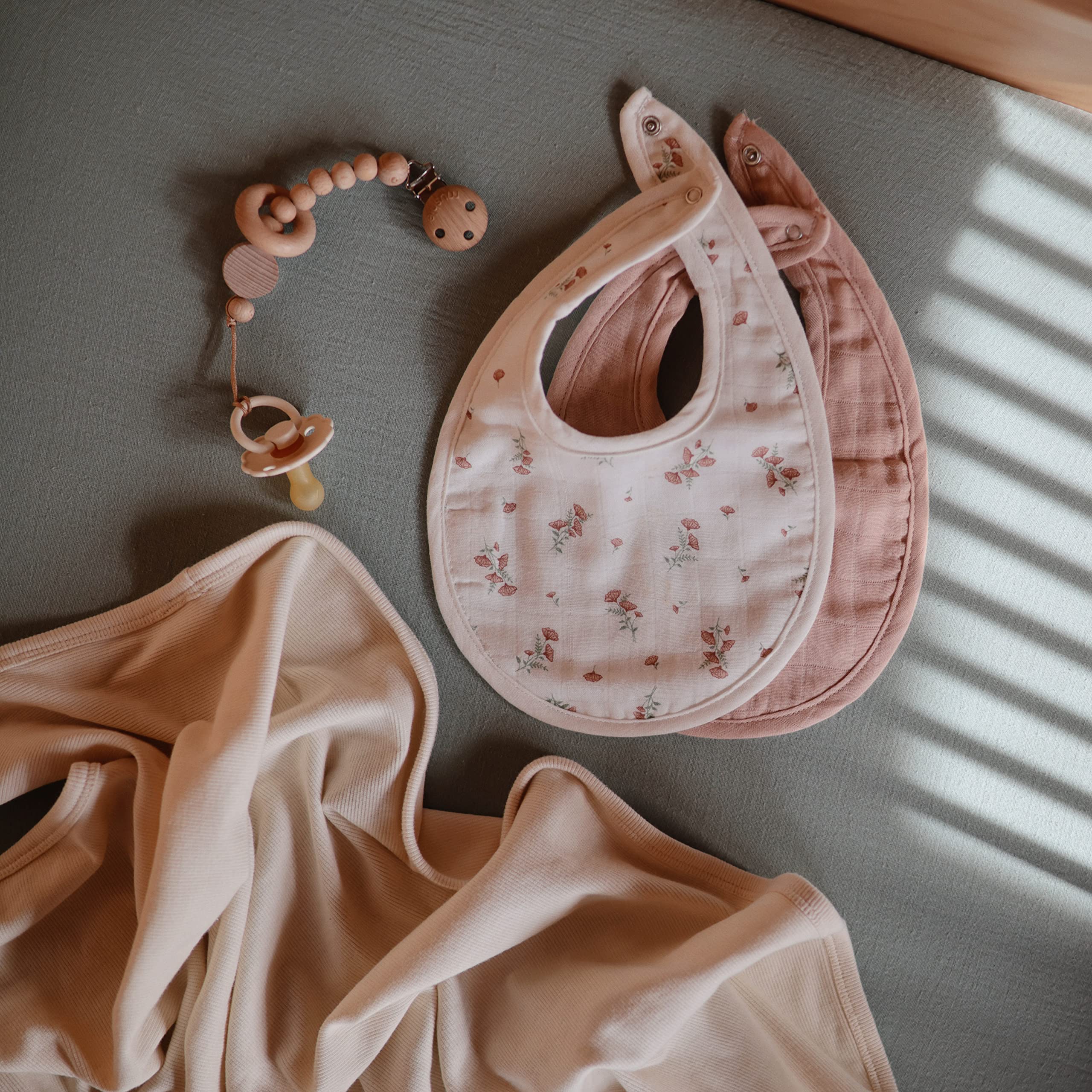 Mushie muslin bib on-baby-meal-time shows drool catch during teething and meals.