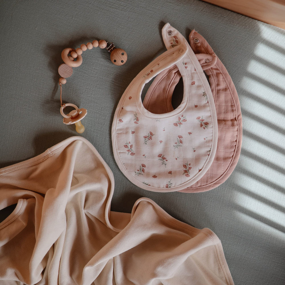 Mushie muslin bib on-baby-meal-time shows drool catch during teething and meals.