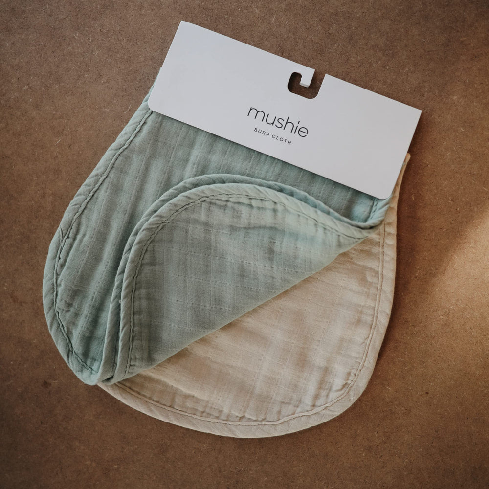 Mushie Muslin Burp Cloths Roman Green on baby, gentle-on-skin and absorbent for spills.