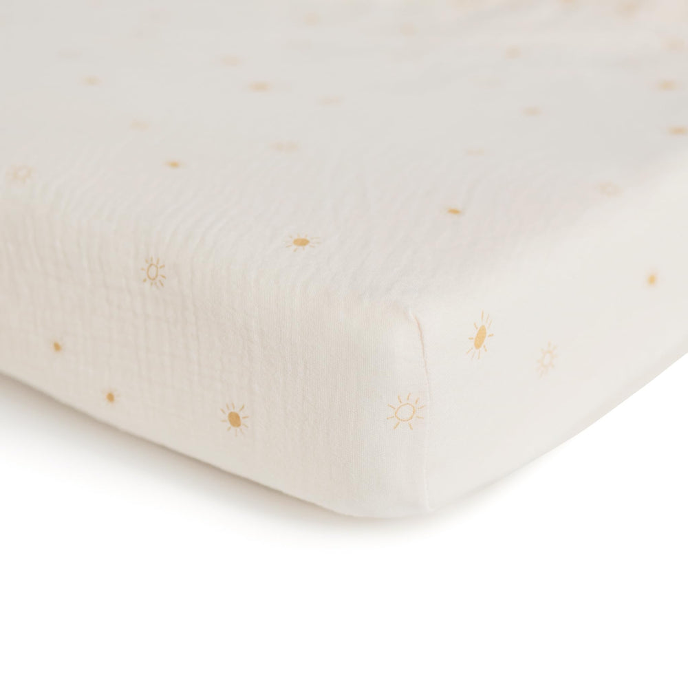 Mushie muslin fitted crib sheet on a crib shows snug fit and easy removal.
