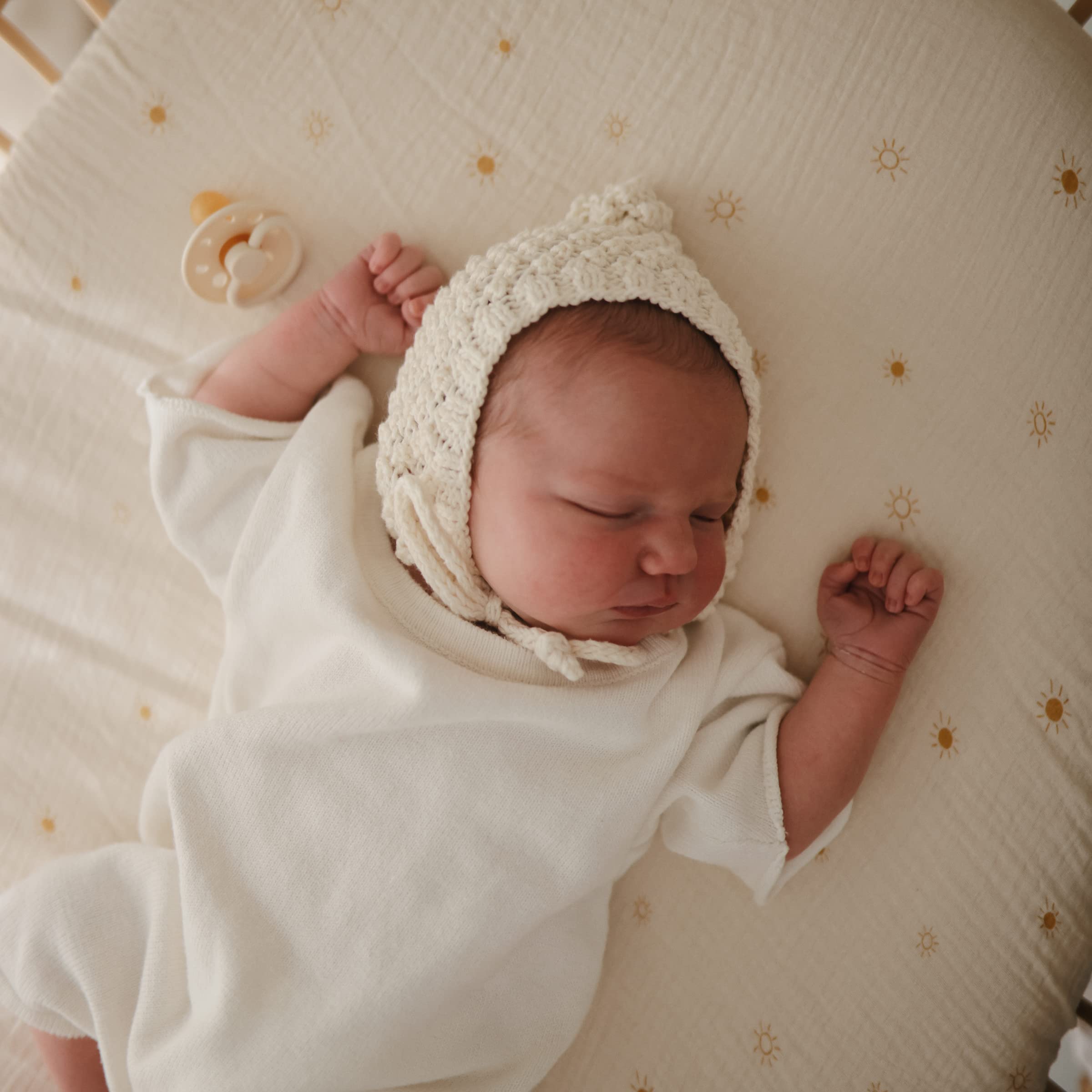 Mushie muslin sheet with elastic edges ensuring a smooth, snug fit on baby mattress.