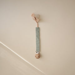Mushie pacifier clip soft fabric strap on olive demonstrates gentle touch for baby comfort
