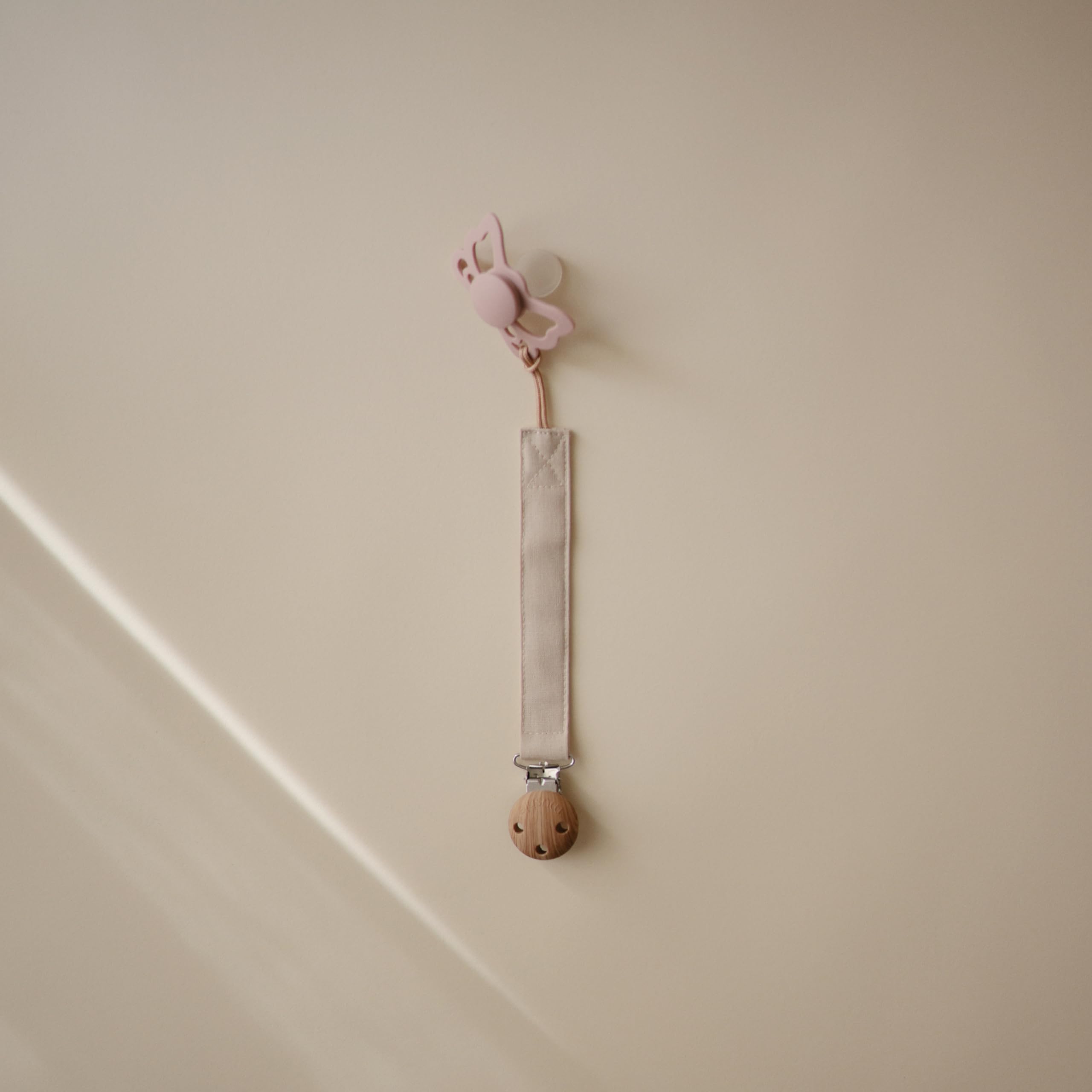 Mushie two-pack pacifier clip on-the-go setup with olive and sand colors keeps pacifiers handy