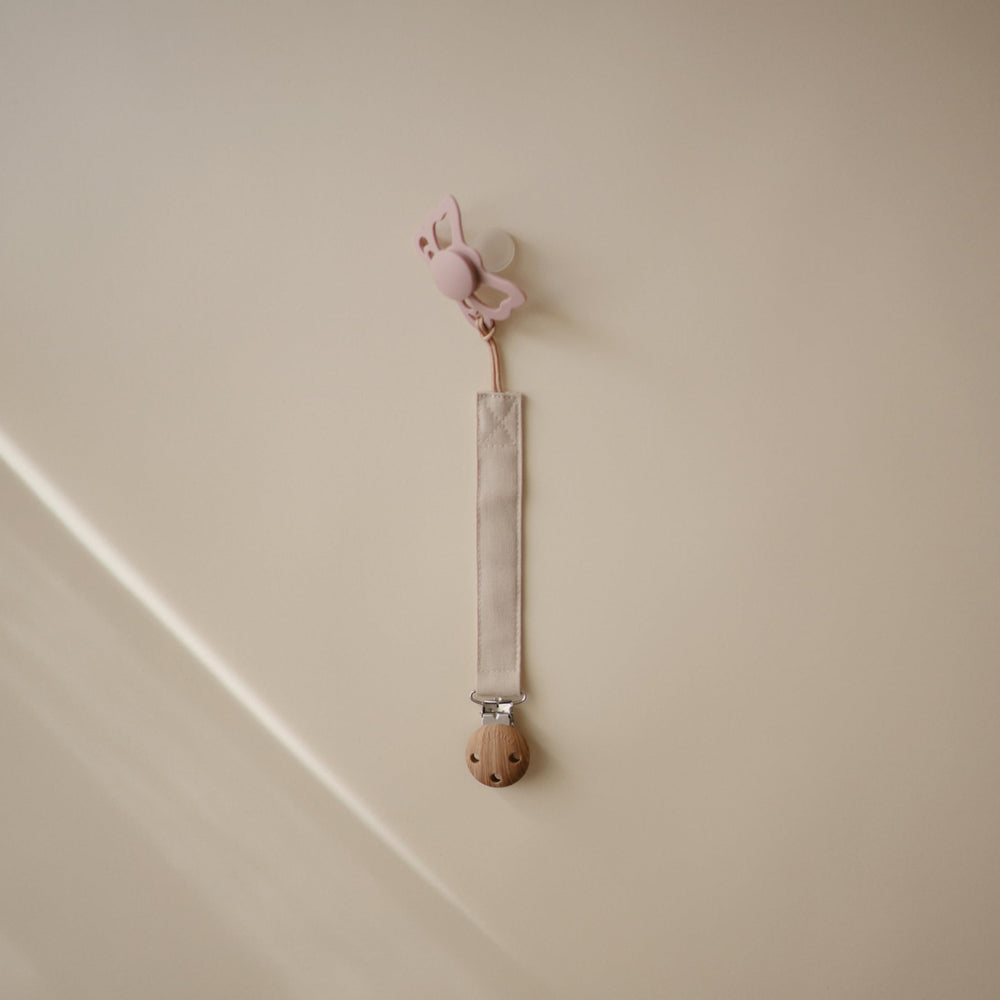 Mushie two-pack pacifier clip on-the-go setup with olive and sand colors keeps pacifiers handy