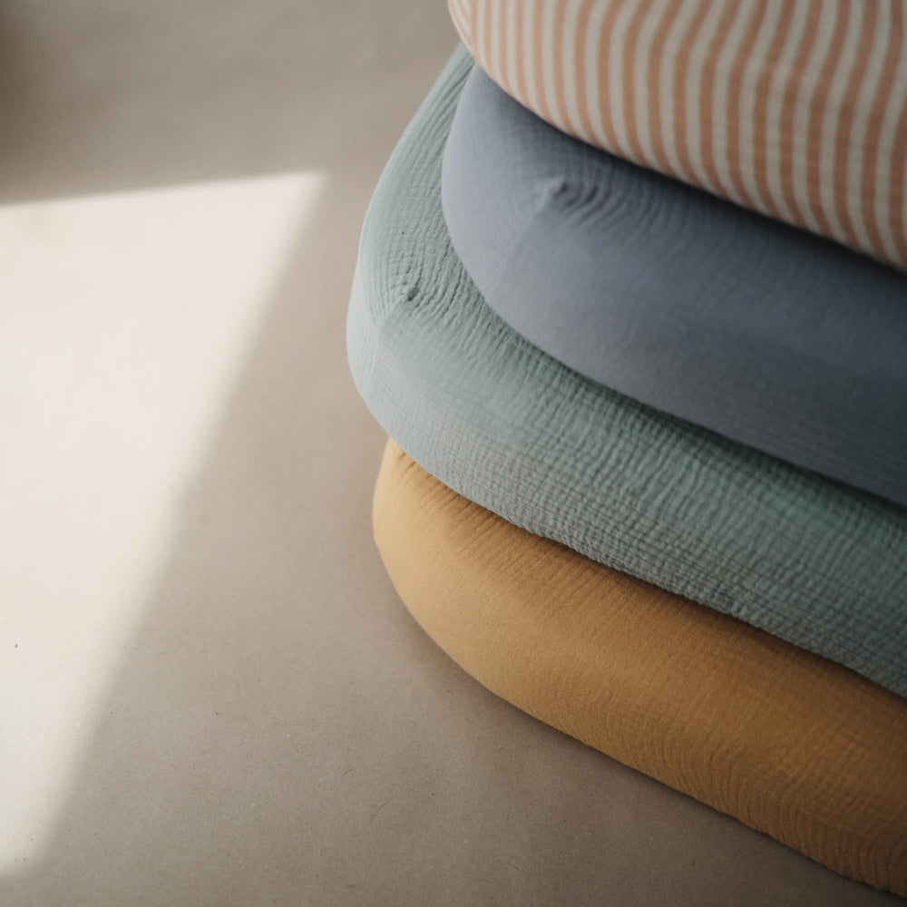 Mushie roman green muslin fabric closeup texture emphasizing softness and airiness.
