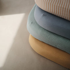 Mushie roman green muslin fabric closeup texture emphasizing softness and airiness.