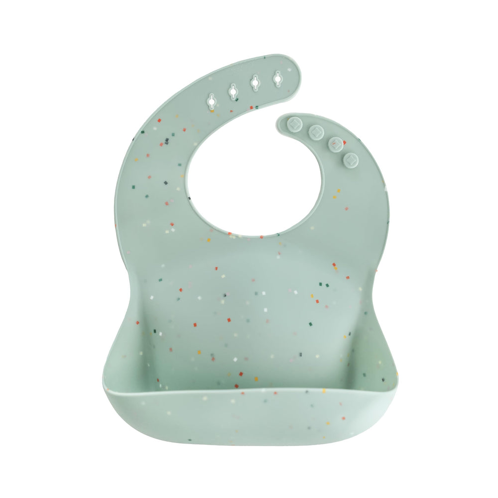 Mushie silicone baby bib with adjustable neck-closure catches spills during meals.