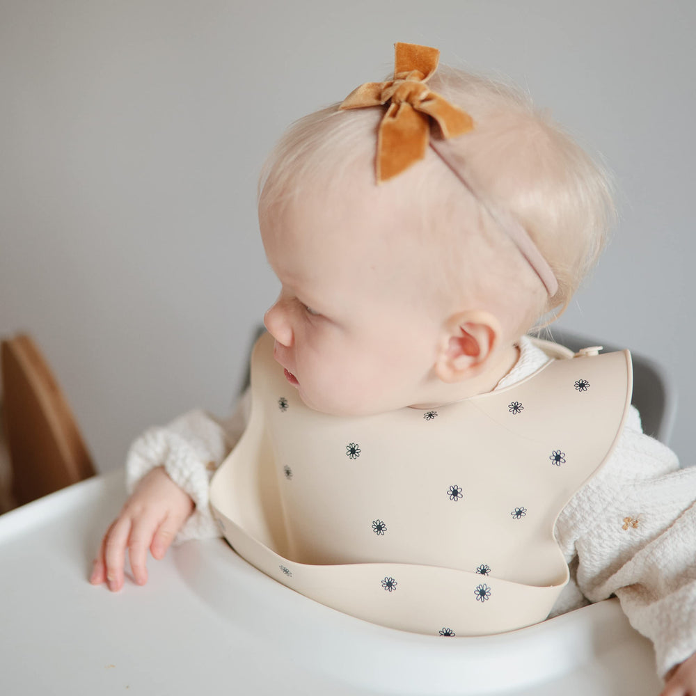 Mushie Black Daisy bib waterproof surface resists stains and wipes clean.
