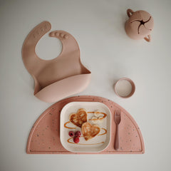 Mushie blush bib has an easy-clean surface that resists stains after meals.