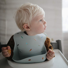 Mushie bib features a deep front pocket to catch spills