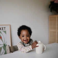 Mushie silicone baby bib deep pocket catching crumbs during feeding times.