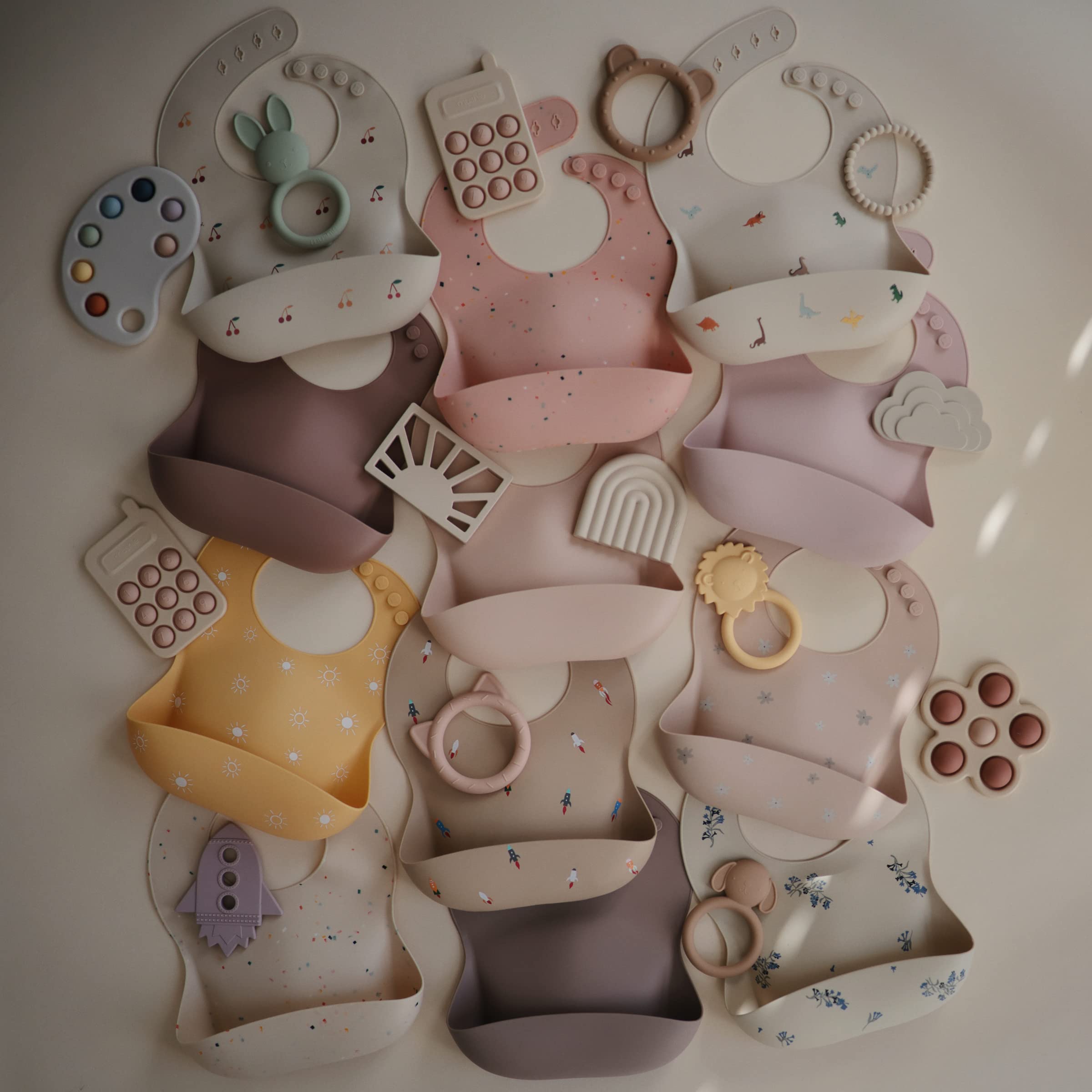 Mushie dusty rose bib beside placemats and tableware for coordinated mealtime