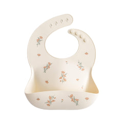 Mushie silicone baby bib pink flowers front view with crumb-catching pocket
