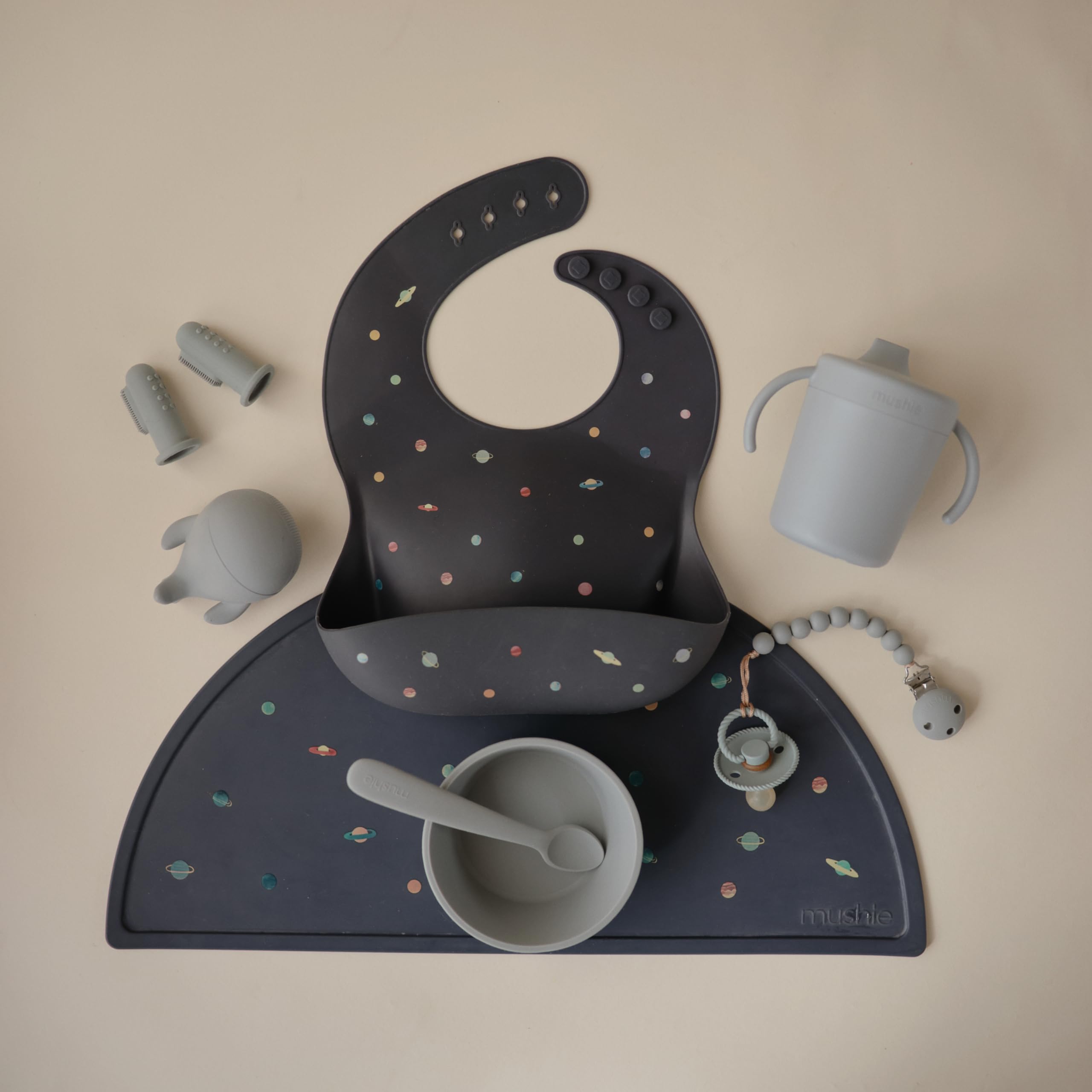 Mushie Planets bib pocket catching crumbs to keep meals mess-free.