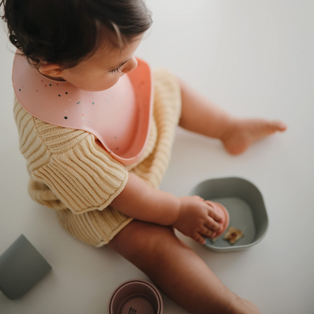 Mushie silicone baby bib powder pink confetti neck-fasteners secure a comfy fit