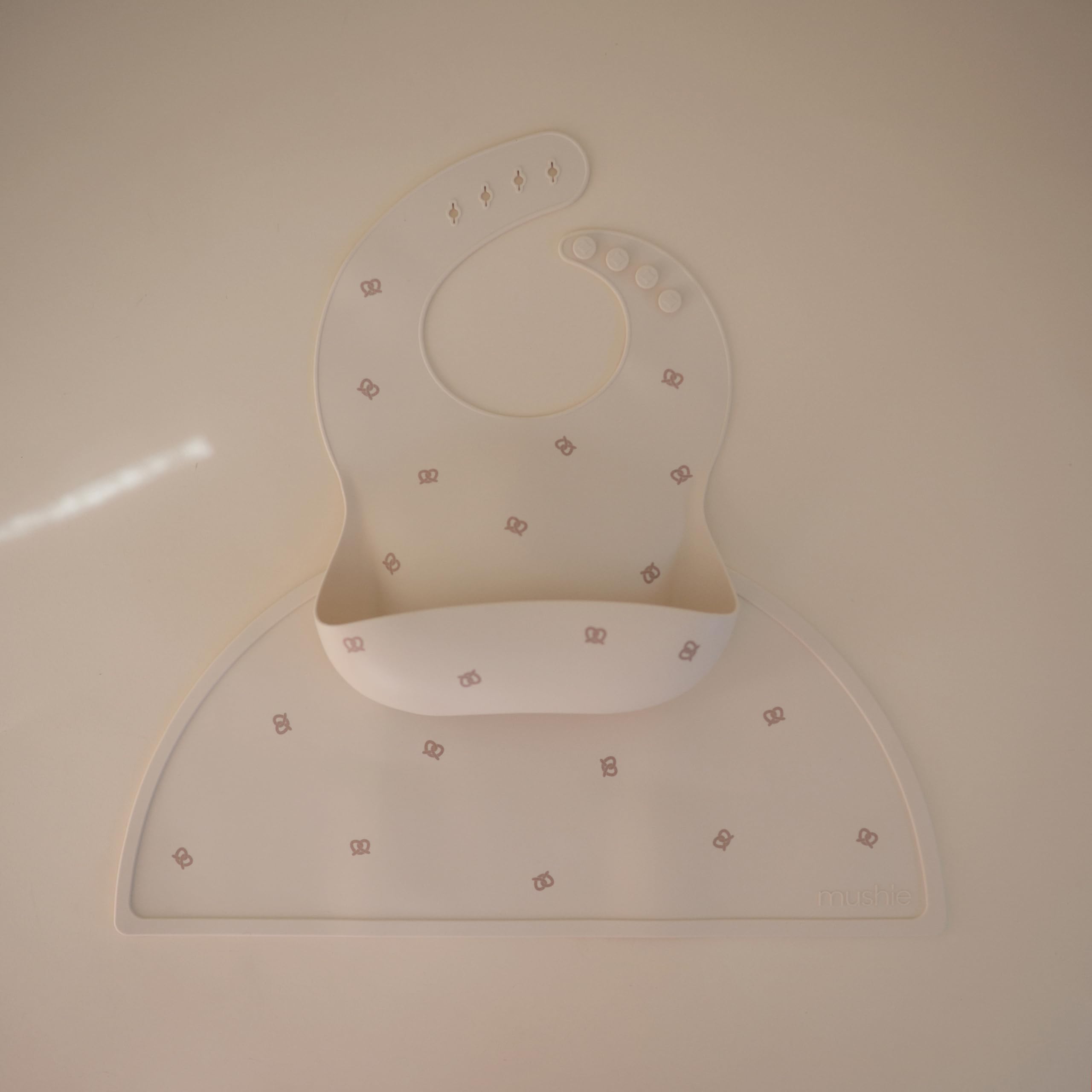 Mushie silicone baby bib Pretzel pocket full ready to catch spills.
