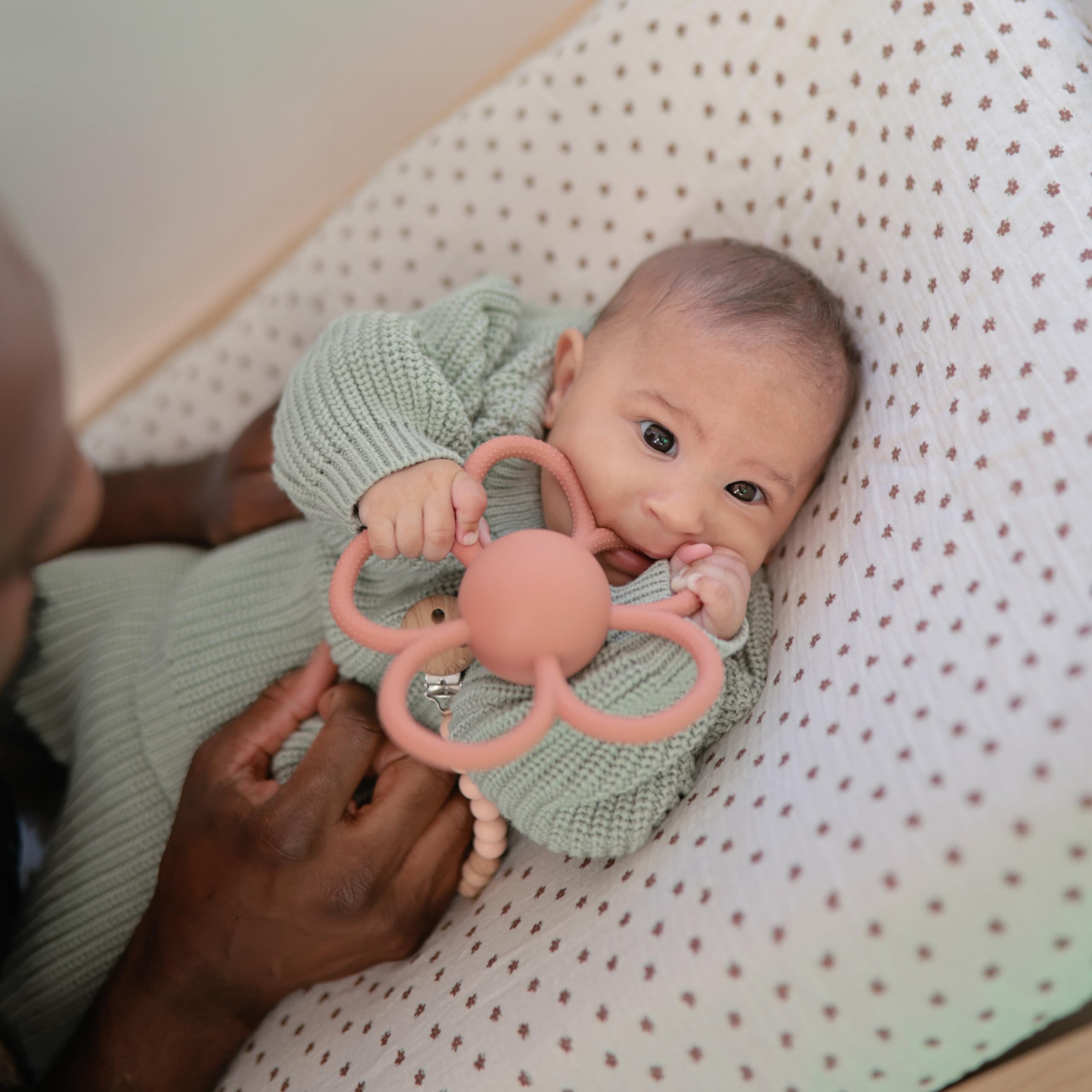 Mushie Daisy Rattle Teether rattling action engages baby attention.
