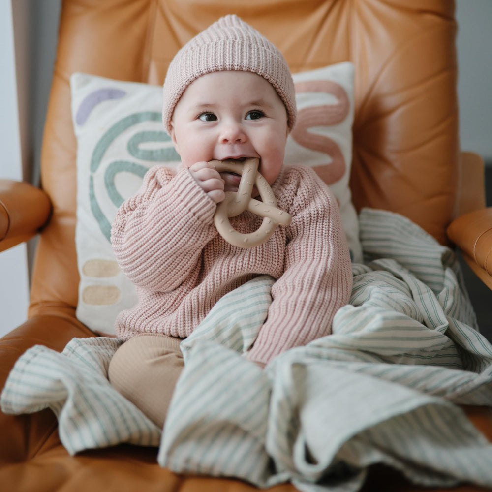 Mushie silicone teether pretzel texture closeup emphasizes varied bite textures.