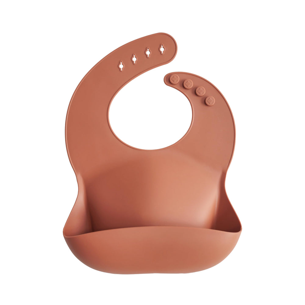 Mushie silicone bib clay on baby wearing for comfortable mealtime with adjustable neck