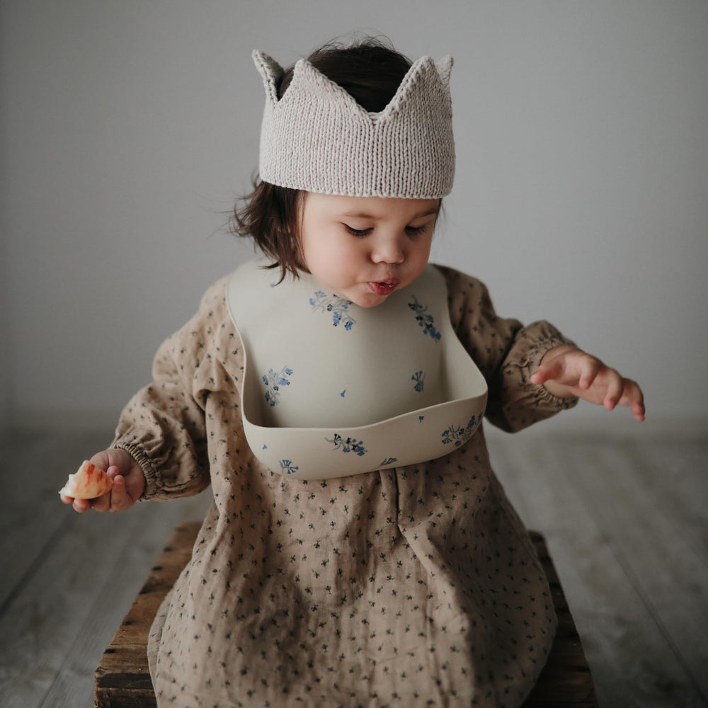 Mushie Lilac Flowers bib demonstrates adjustable-fit concept for growing babies.