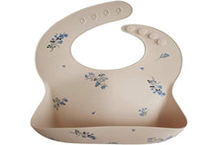 Mushie Lilac Flowers bib on table highlighting stain-resistant surface for quick wipe-down.