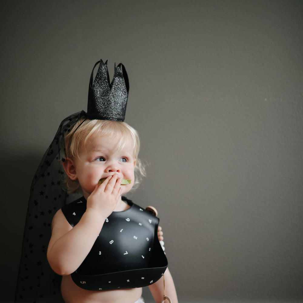 Mushie silicone bib Numbers Black pocket catcher demonstrates deep front pocket for catching crumbs.