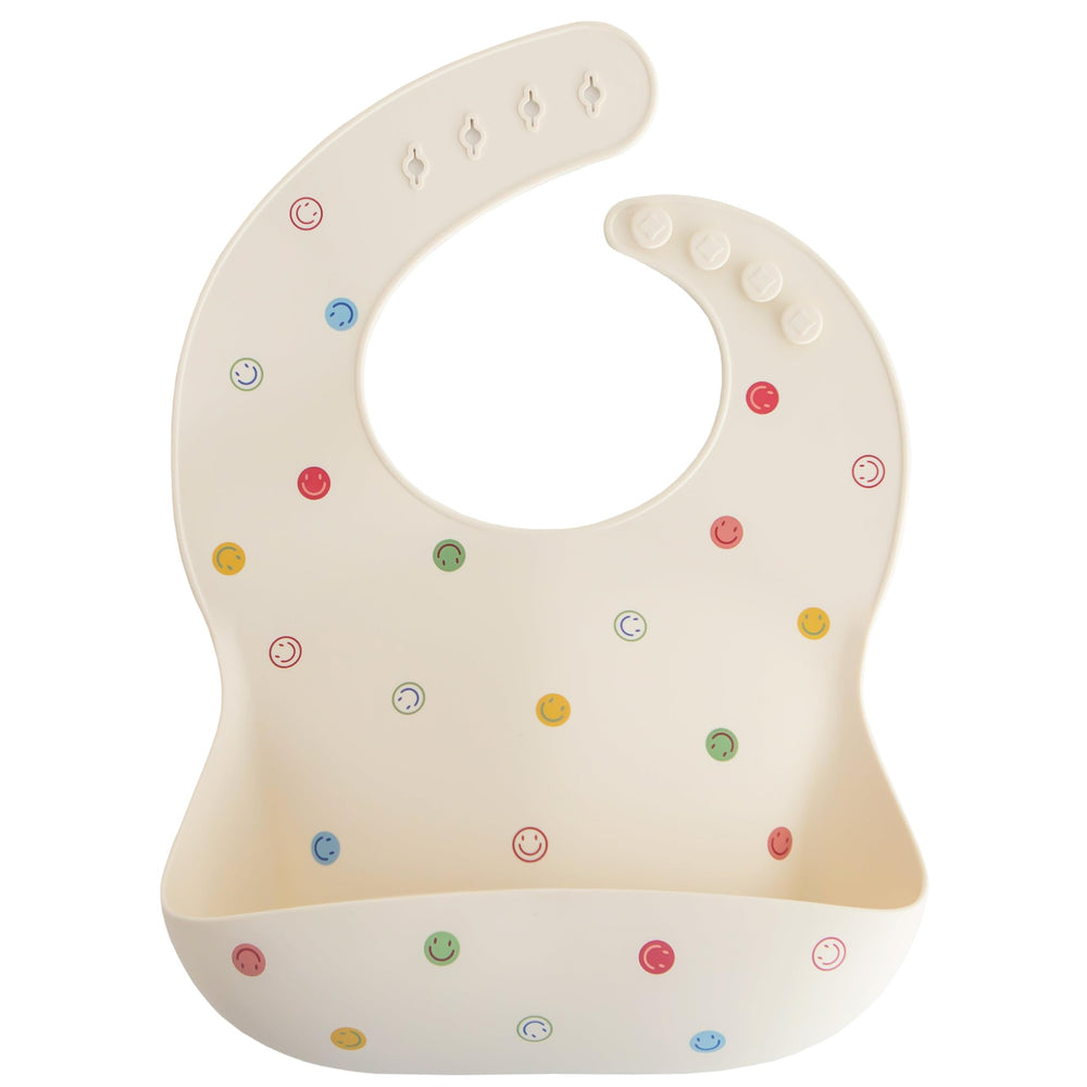 Mushie silicone bib smiley face closeup highlights stain-resistant material