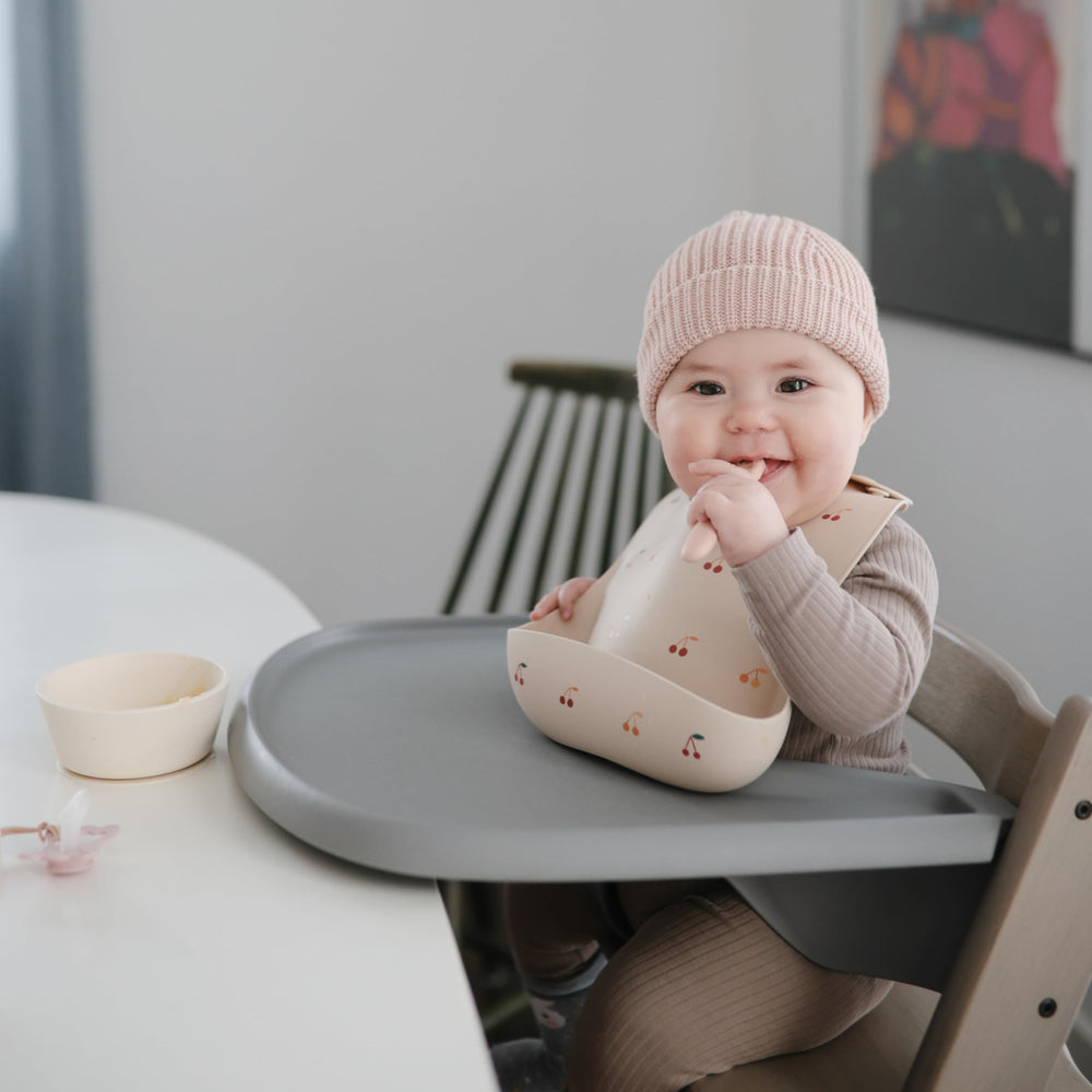 Mushie bib waterproof cherries keeps clothes clean between wipes.