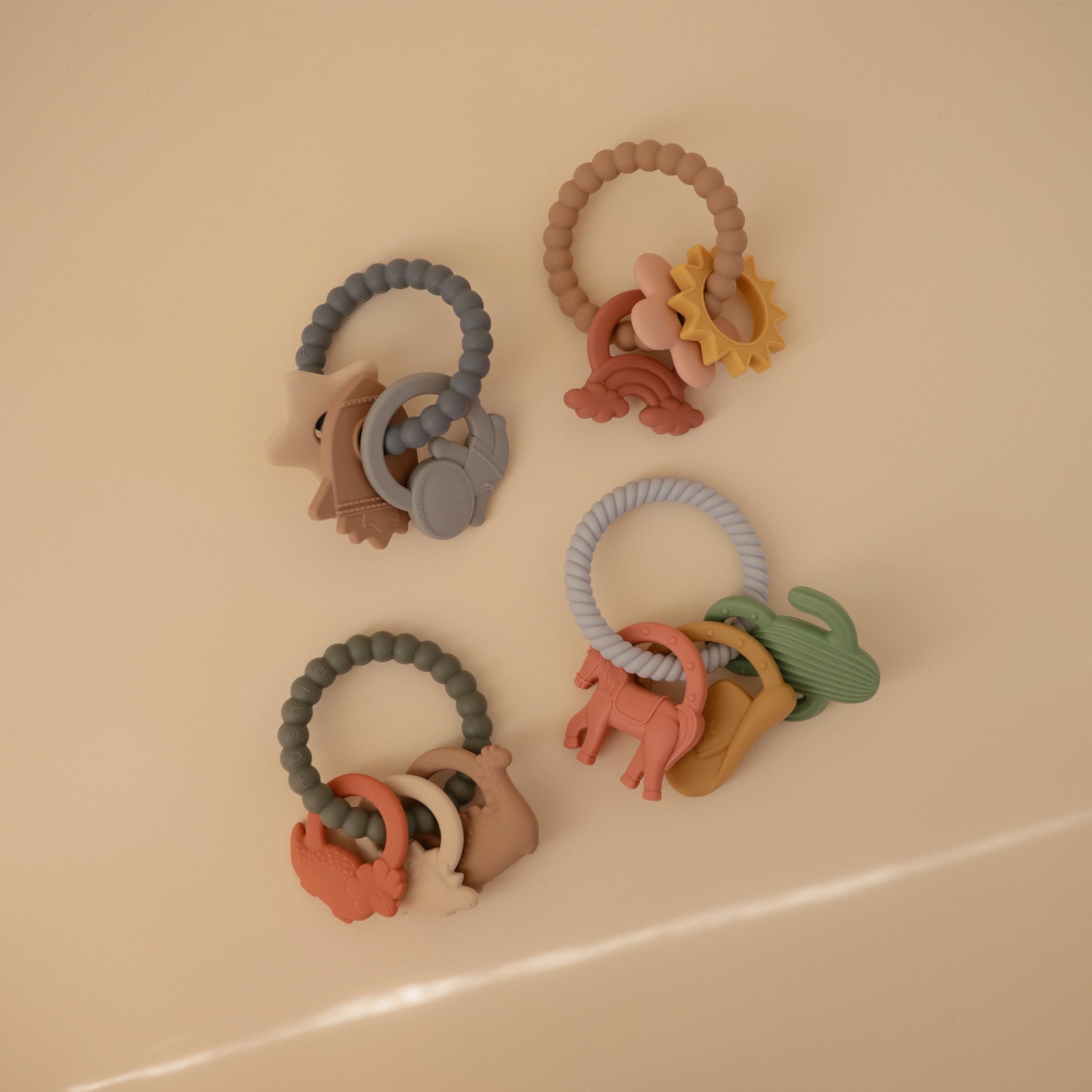 Mushie silicone dino teething ring back view highlighting three dinosaur shapes