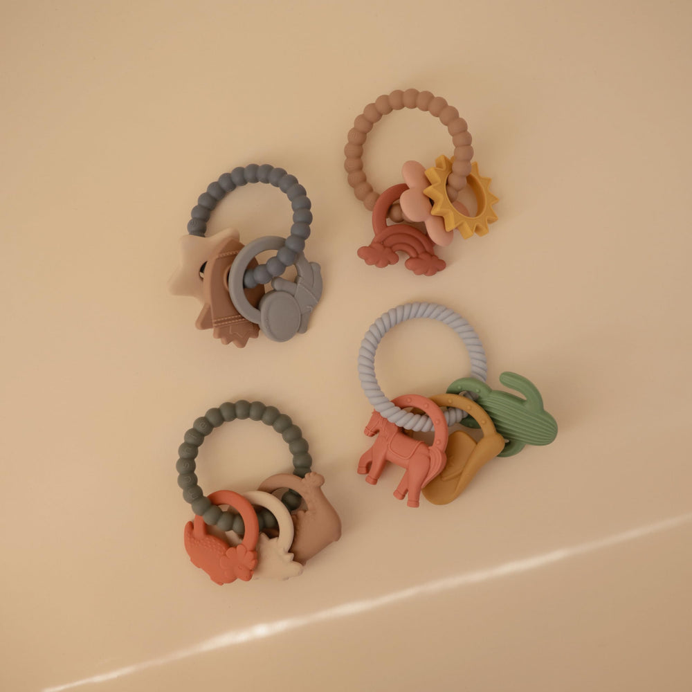 Mushie silicone dino teething ring back view highlighting three dinosaur shapes