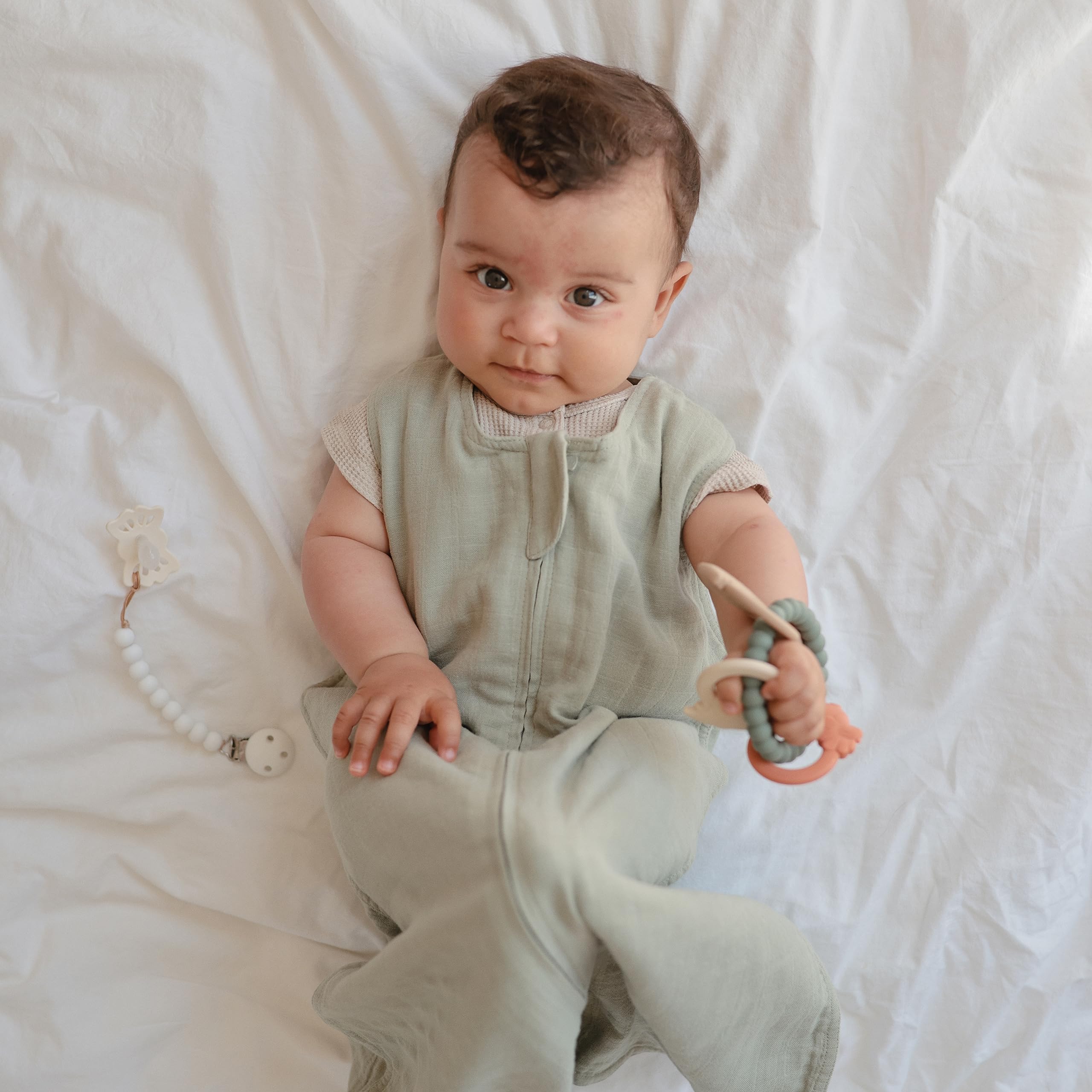 Mushie silicone dino teething ring in baby hand for easy handling