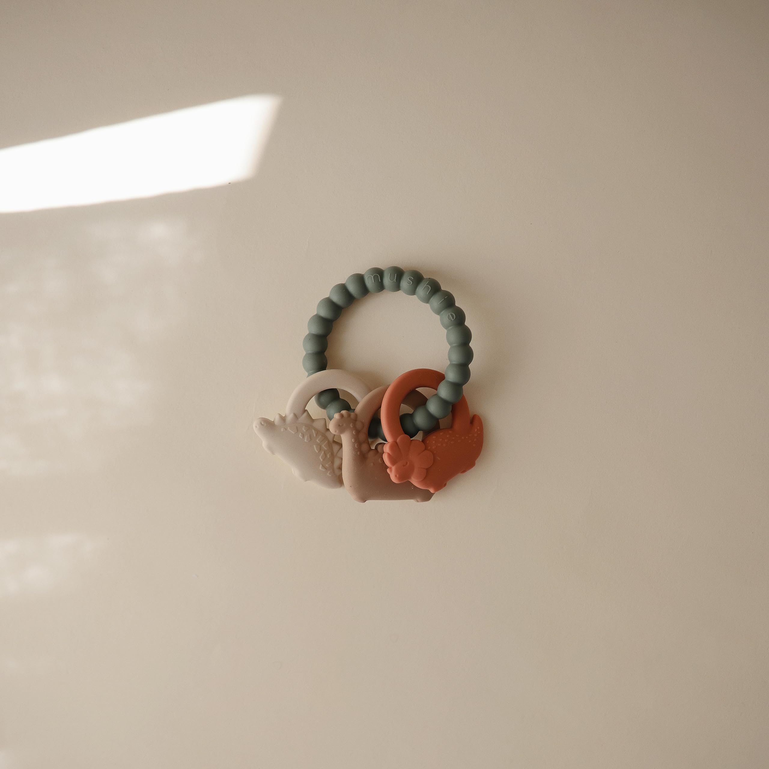 Mushie silicone dino teething ring side view with easy grip for little hands