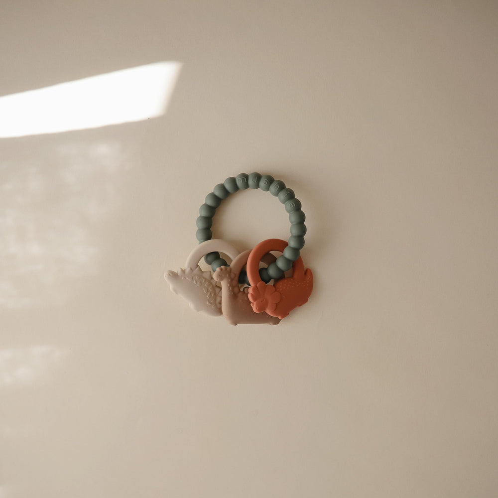 Mushie silicone dino teething ring side view with easy grip for little hands