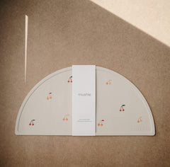 Mushie placemat cherries close up showing stain resistant, wipe clean design for quick cleanup.