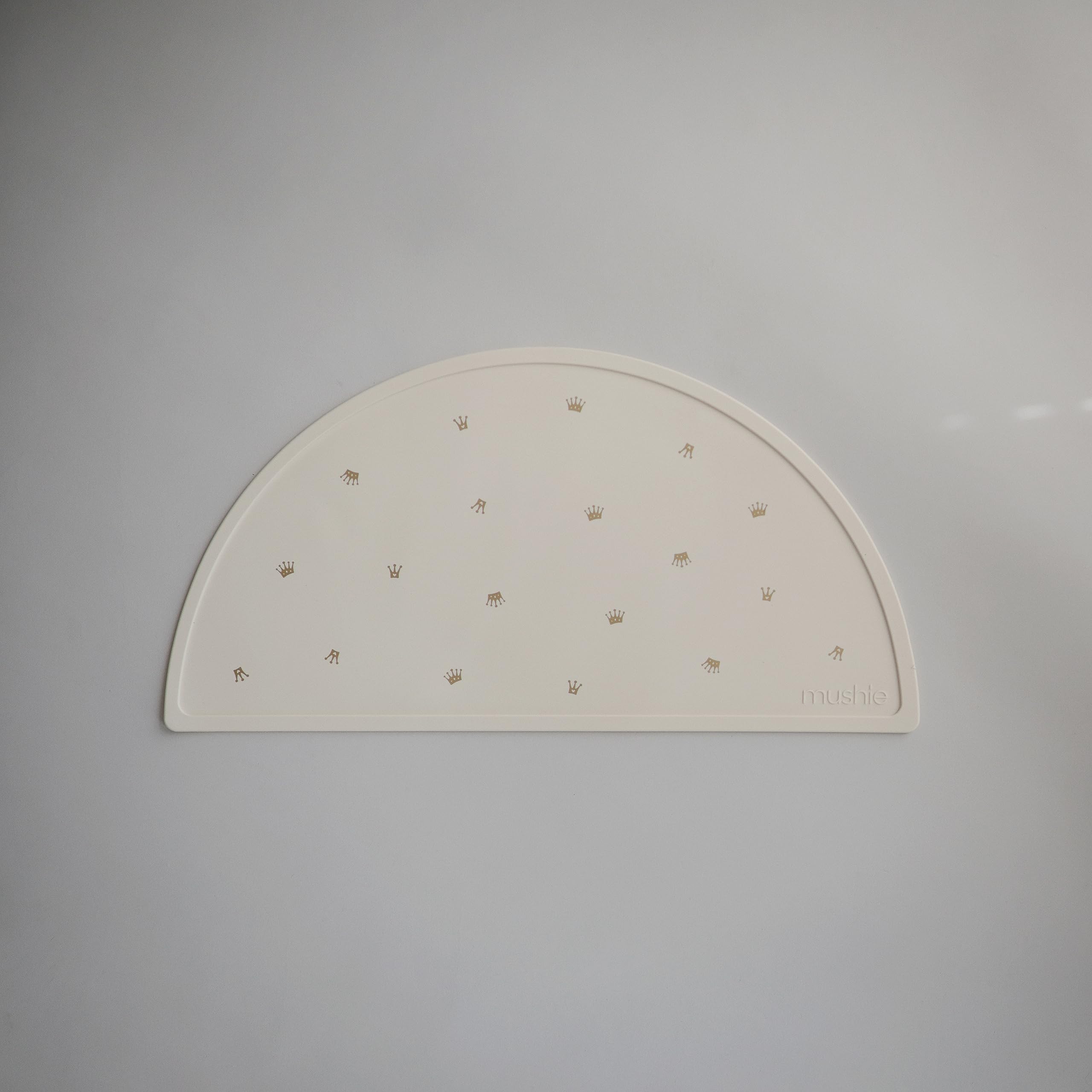 Mushie silicone placemat crowns flatlay shows vibrant design and stain resistance.