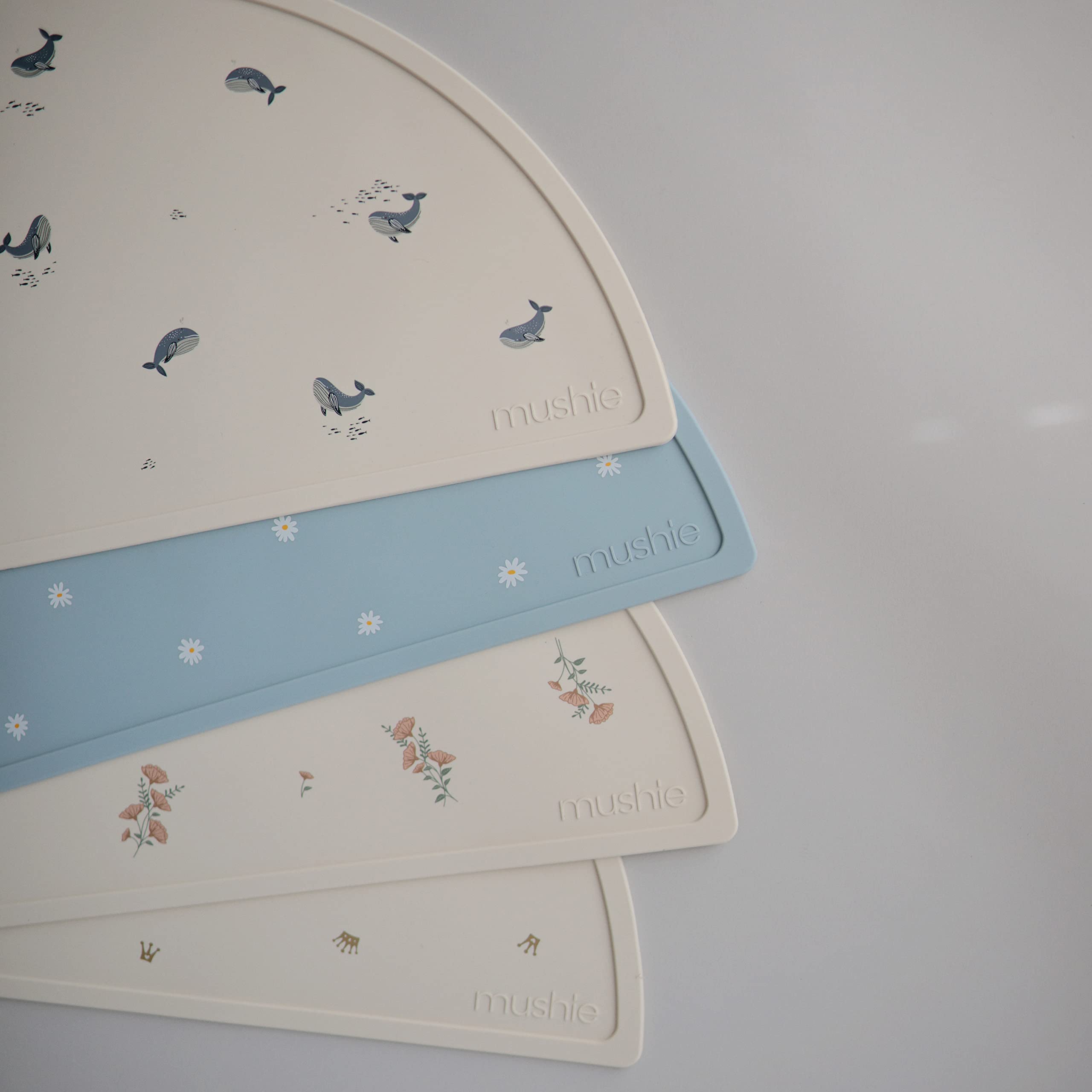 Mushie silicone placemat crowns wipe-clean after meals.