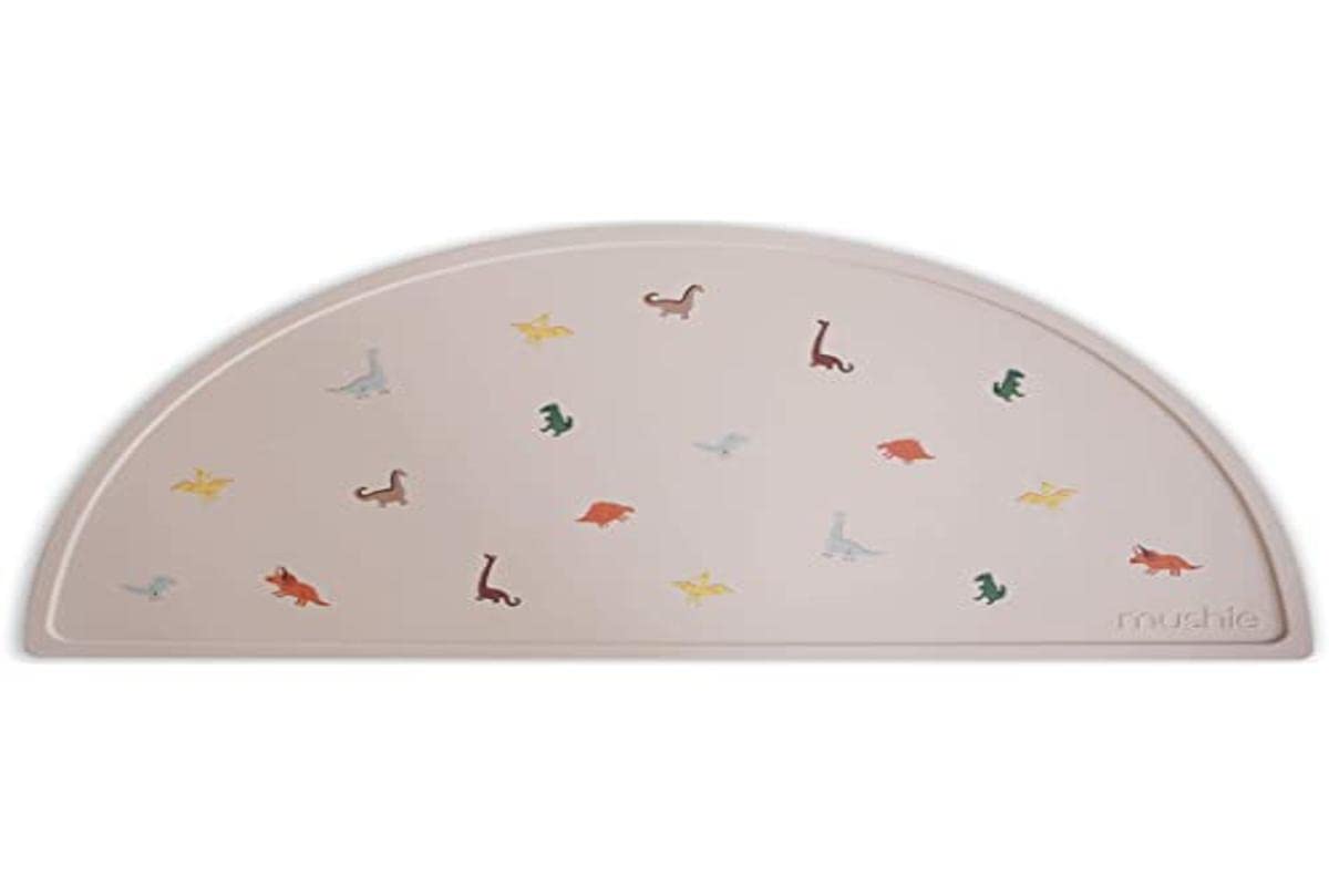 Mushie silicone placemat dinosaurs; easy-clean, water-repellent surface for quick post-meal cleanup.