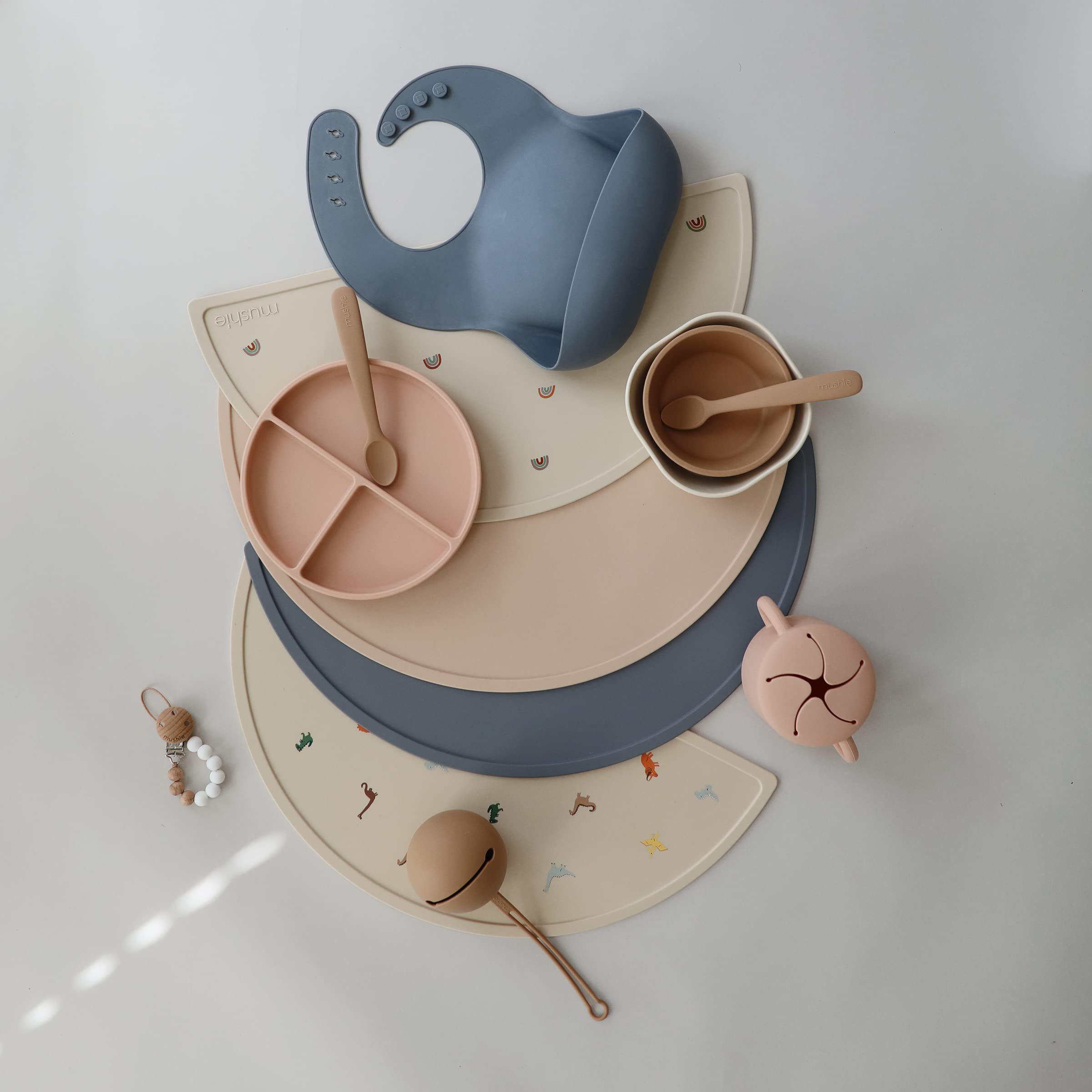Mushie silicone placemat dinosaurs; vibrant design pairs with Mushie bibs and pacifiers.