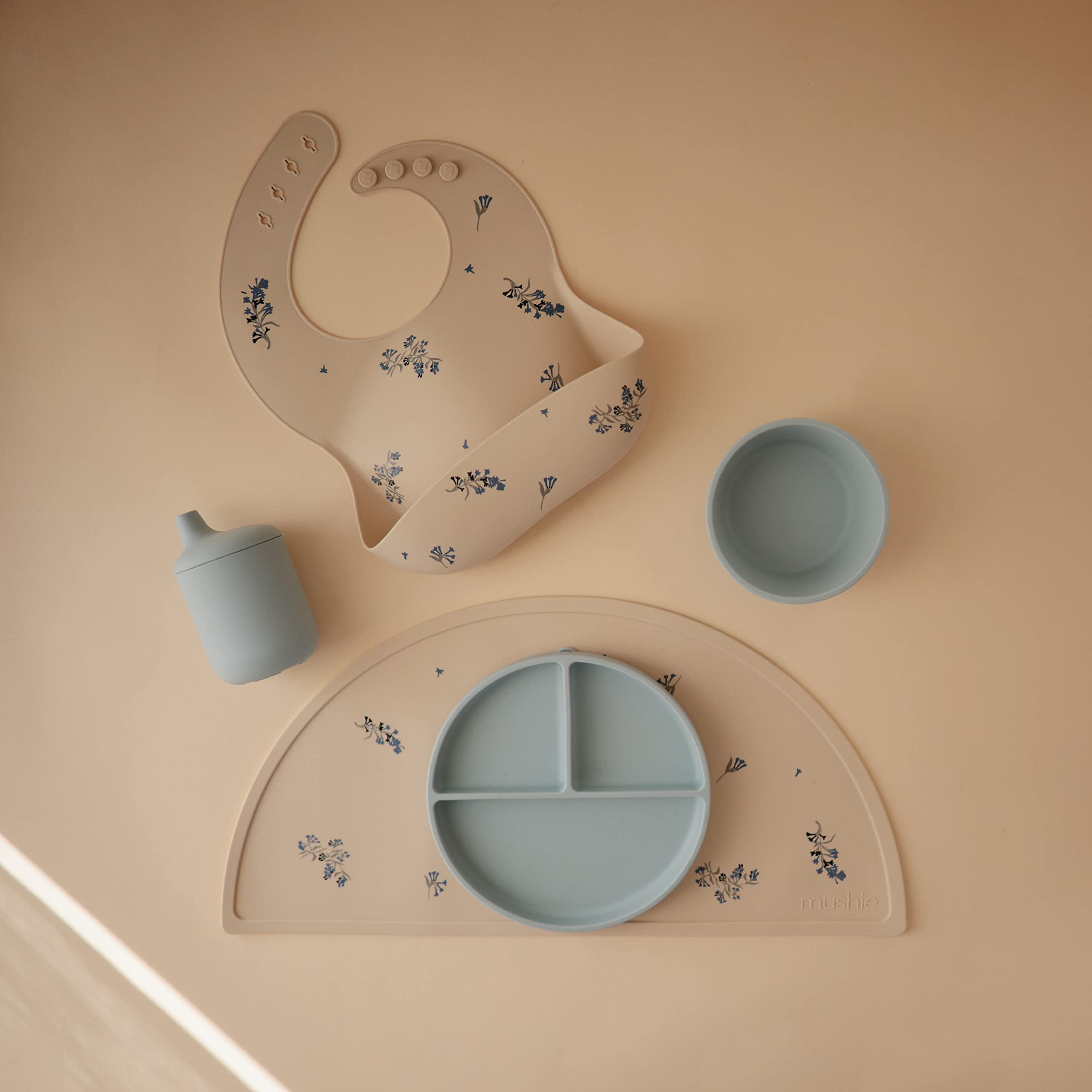 Mushie silicone placemat Lilac Flowers dishwasher-safe badge for quick cleaning.