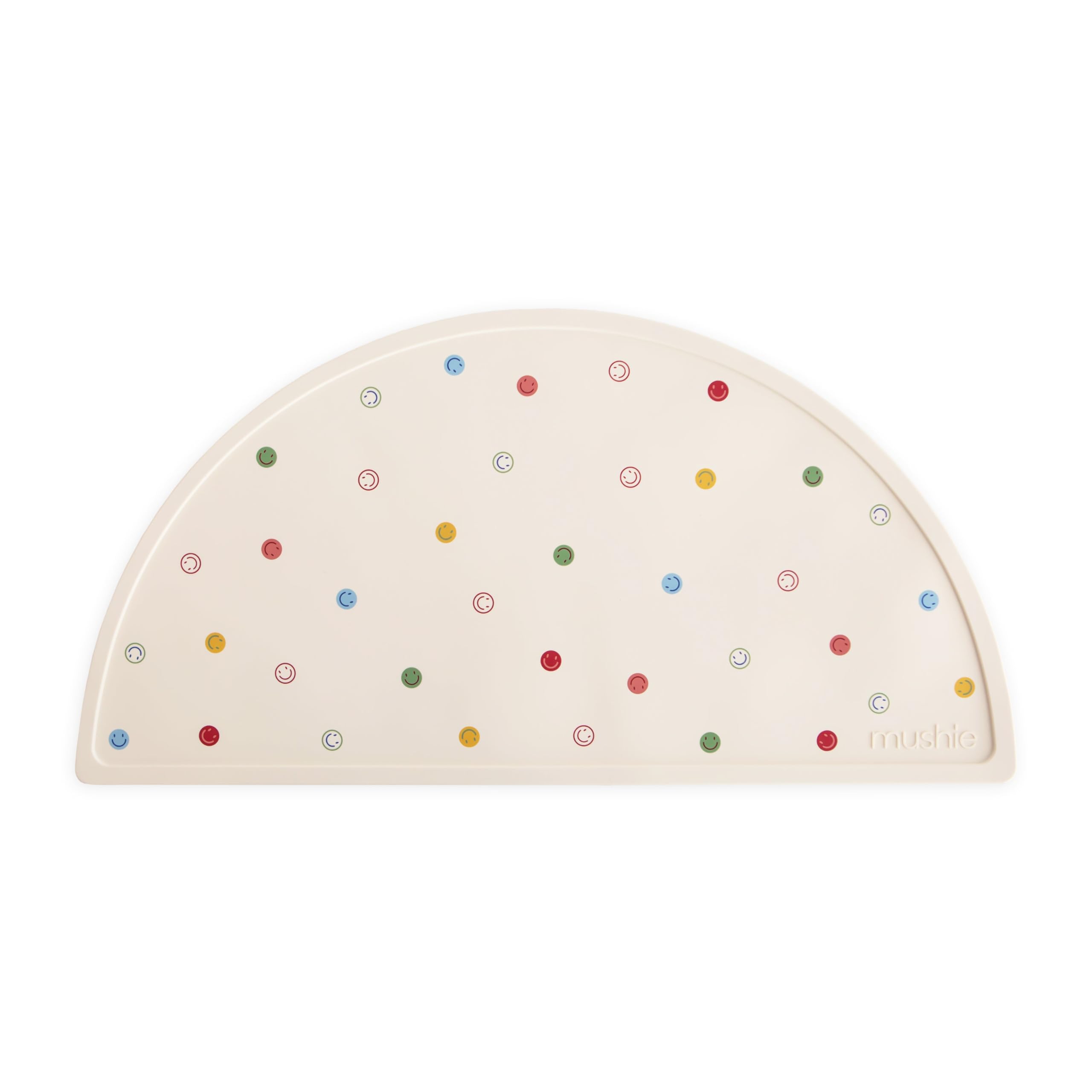 Mushie silicone placemat smiley-face-design promotes cheerful, mess-free mealtimes.
