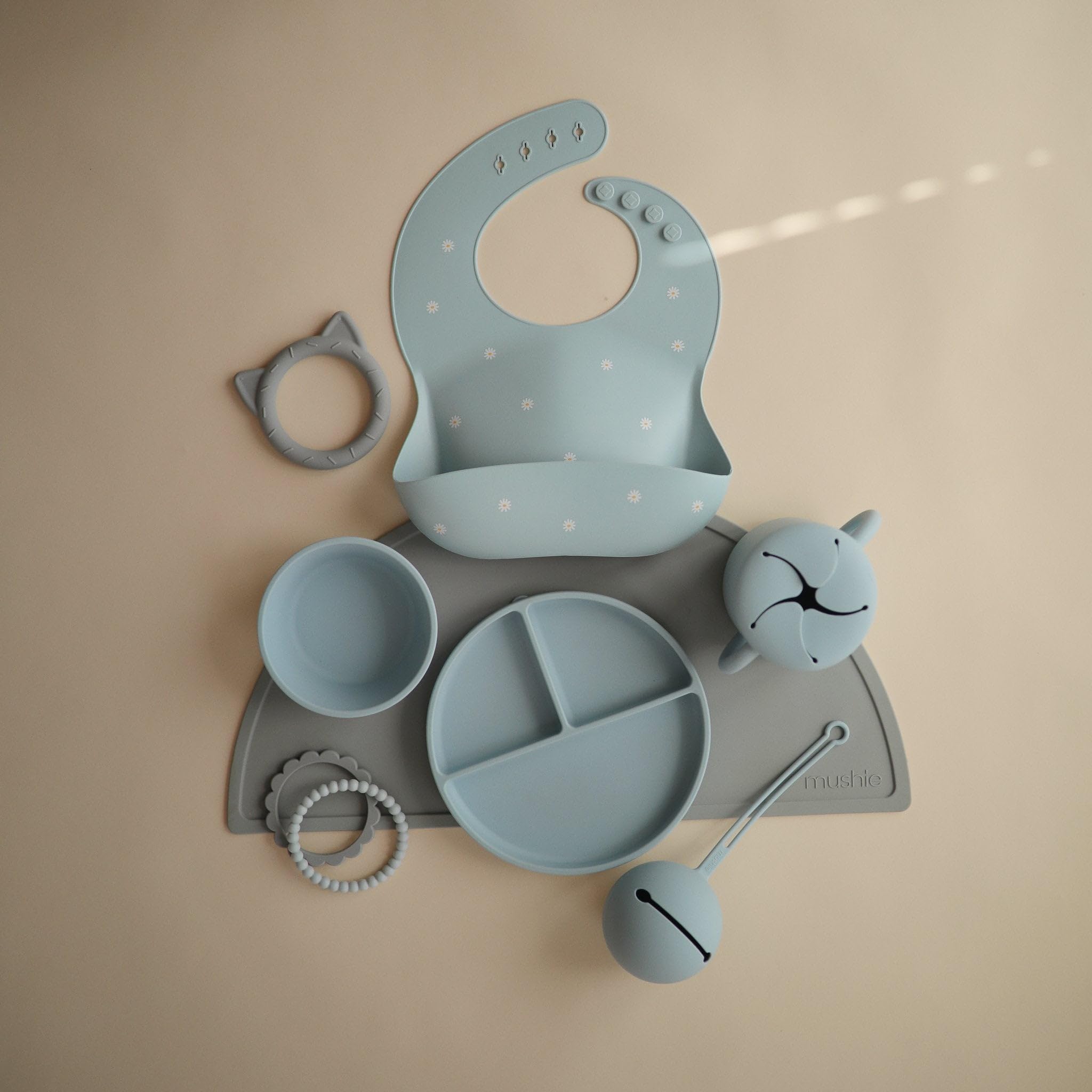 Mushie silicone placemat stone dining-table scene highlights easy wipe-clean maintenance.