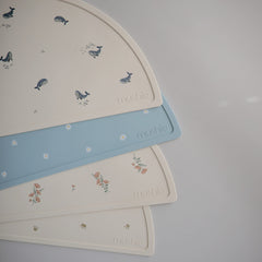 Mushie silicone placemat whales on table demonstrates non-slip stability during meals.