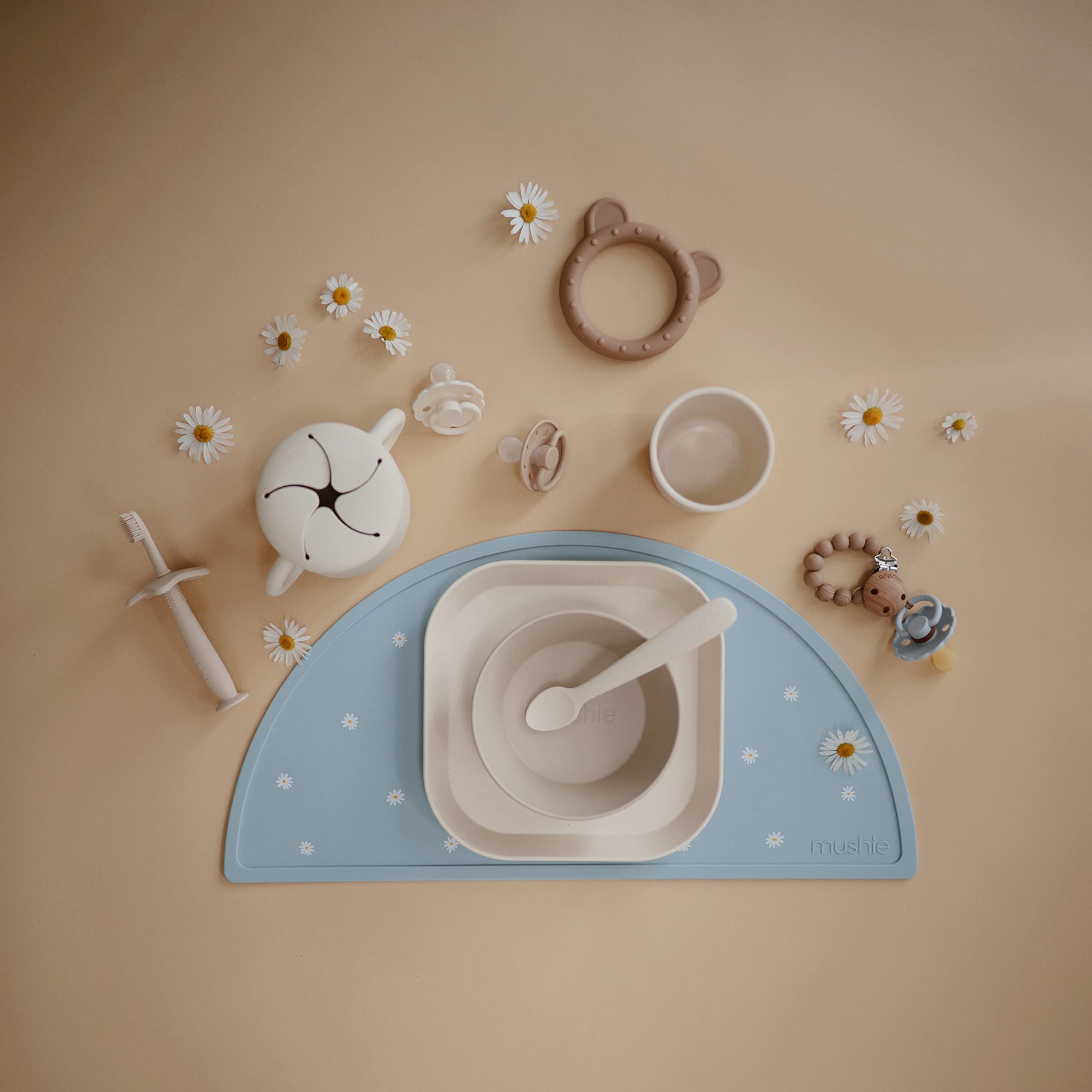 Mushie Ivory snack cup being washed by hand emphasizes gentle cleaning.
