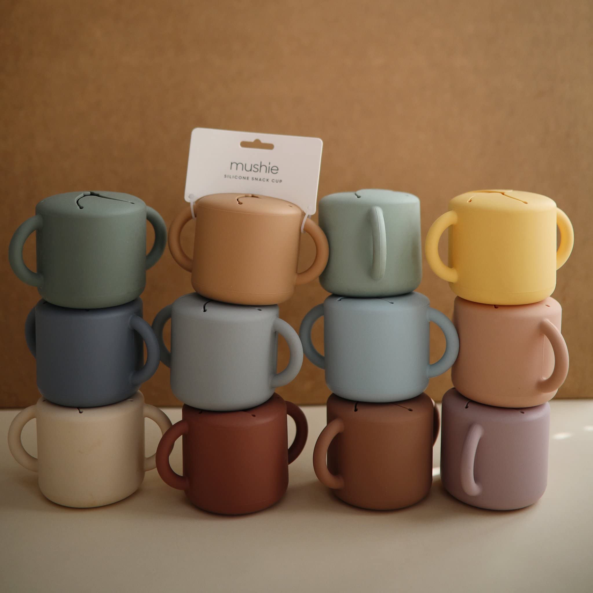 Mushie snack cup ivory in toddler hands demonstrates self-feeding-friendly design.