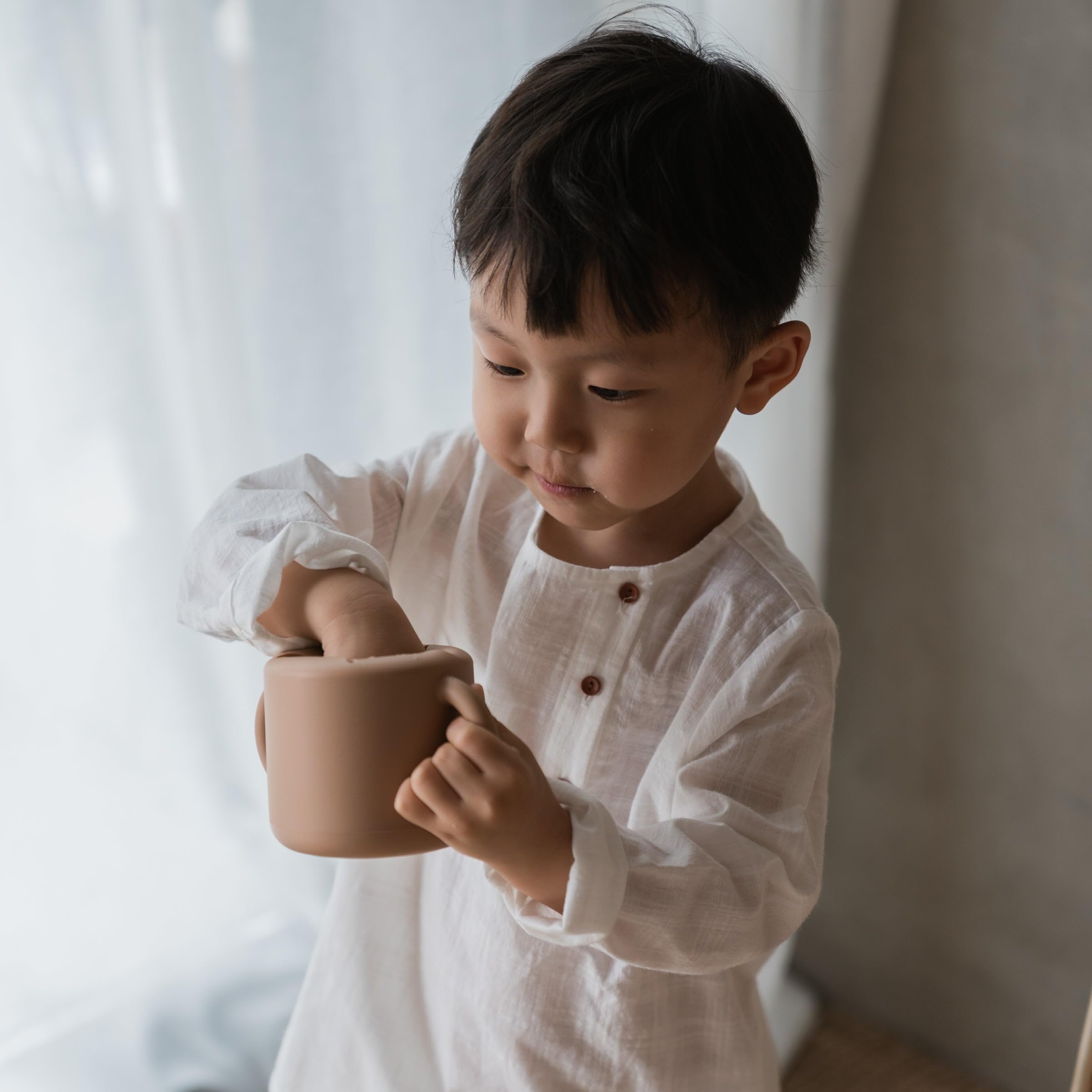 Mushie silicone snack cup natural in-use demonstrating self-feeding