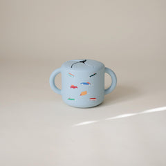 Mushie silicone snack cup, spill-proof design keeps snacks inside during travel.