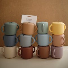 Mushie silicone snack cup whales filled with snacks to illustrate usable capacity.