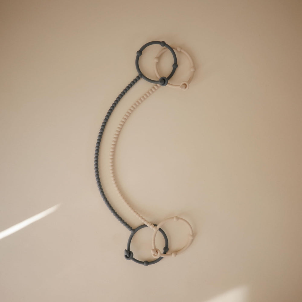 Mushie silicone straps hold a pacifier for easy access and reduced drops.