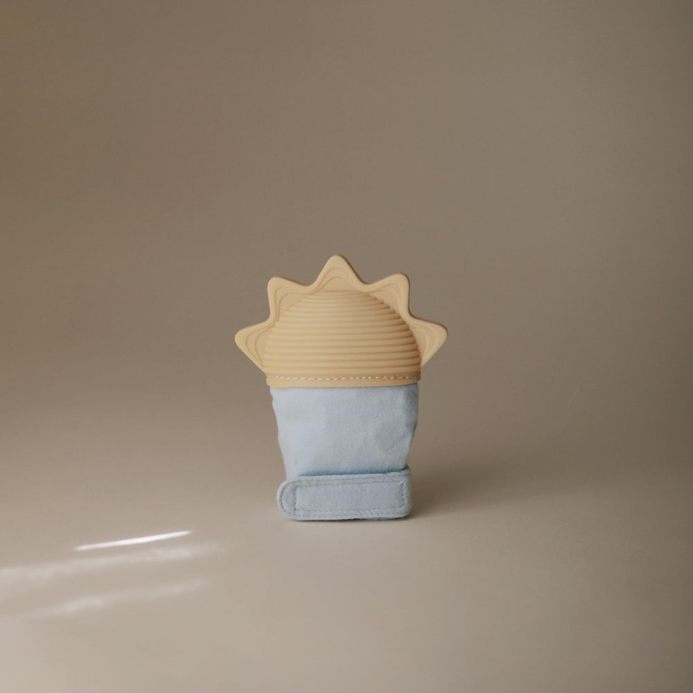 Mushie teething mitten worn on hand for hands-free soothing during teething
